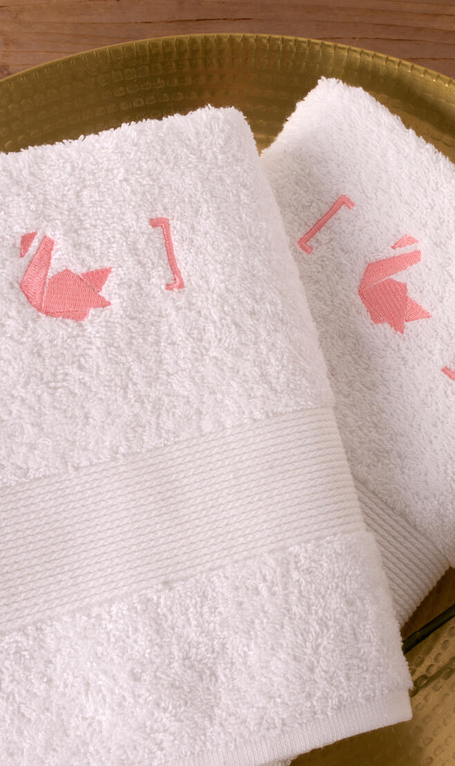 Witte handdoeken met roze borduring op schaaltje